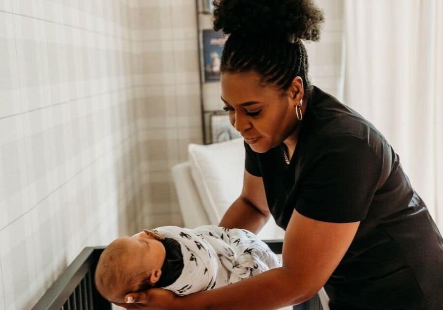Postpartum Doula places swaddled baby to sleep in crib