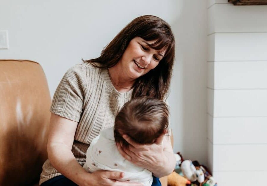 Postpartum Doula holds swaddled baby facing her